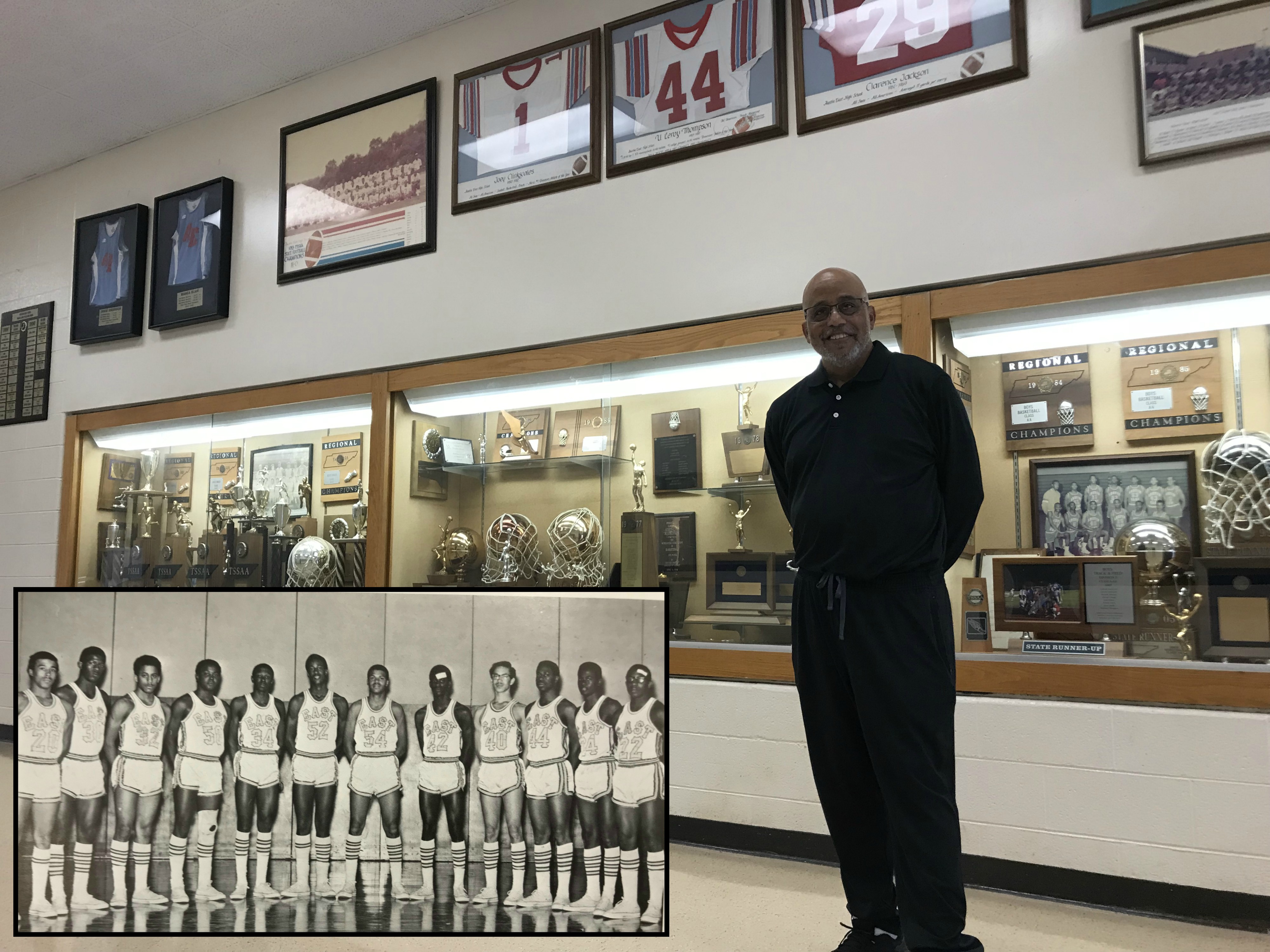 Brian Harvey stands in front of the trophy case at Austin-East High School, his alma mater, on Sep. 17, 2018. At upper left is a yearbook photo, with Harvey third from the left, wearing #32.